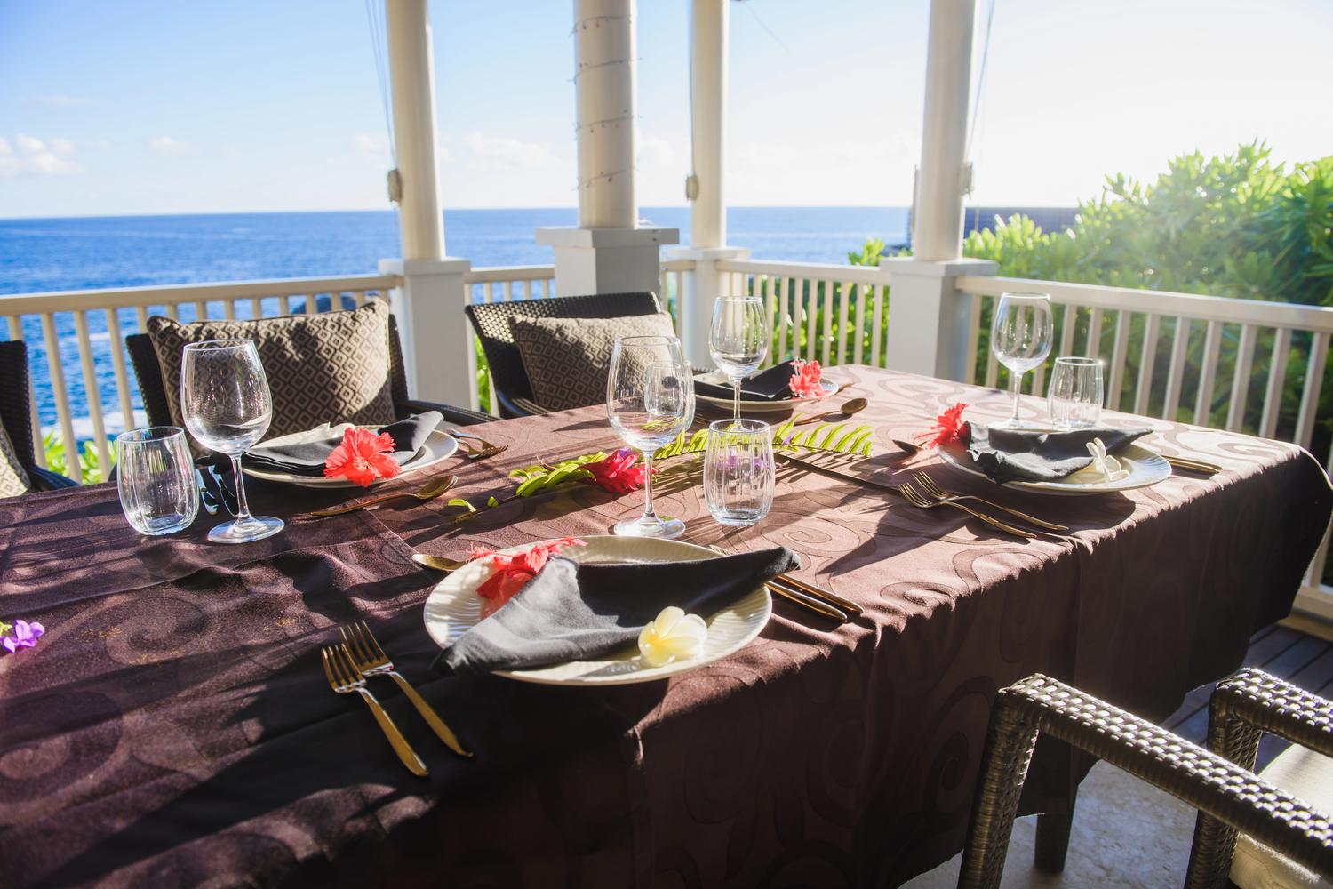A table set for dinner on a veranda overlooking the sea