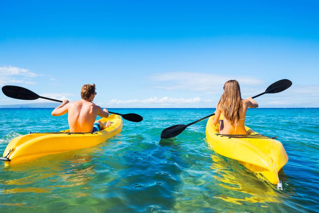 A couple paddling yellow kayaks over clear shallow water