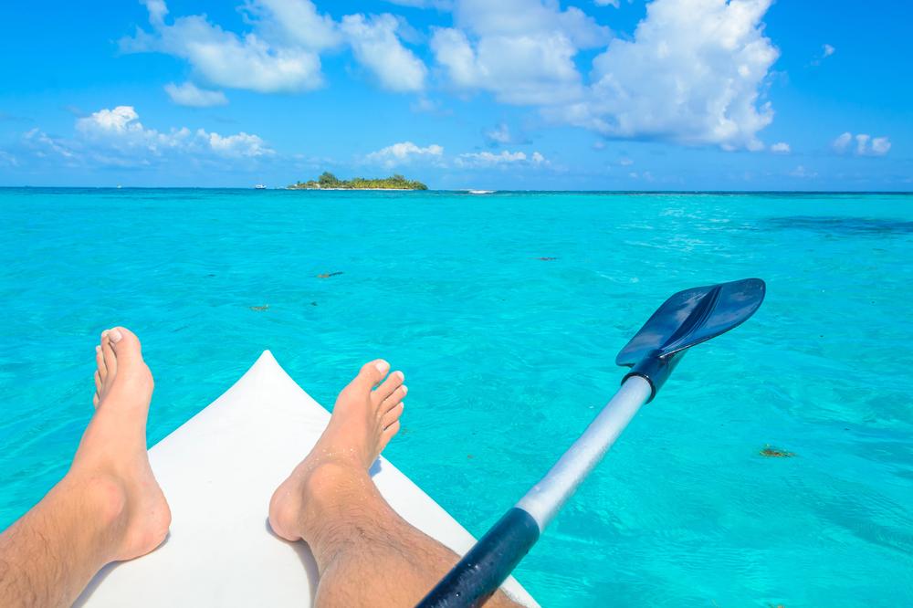 Bare feet on the nose of a paddleboard over turquoise water