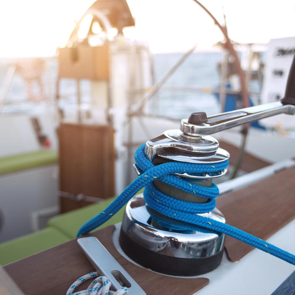 Blue line wrapped around a polished winch on a sailboat deck